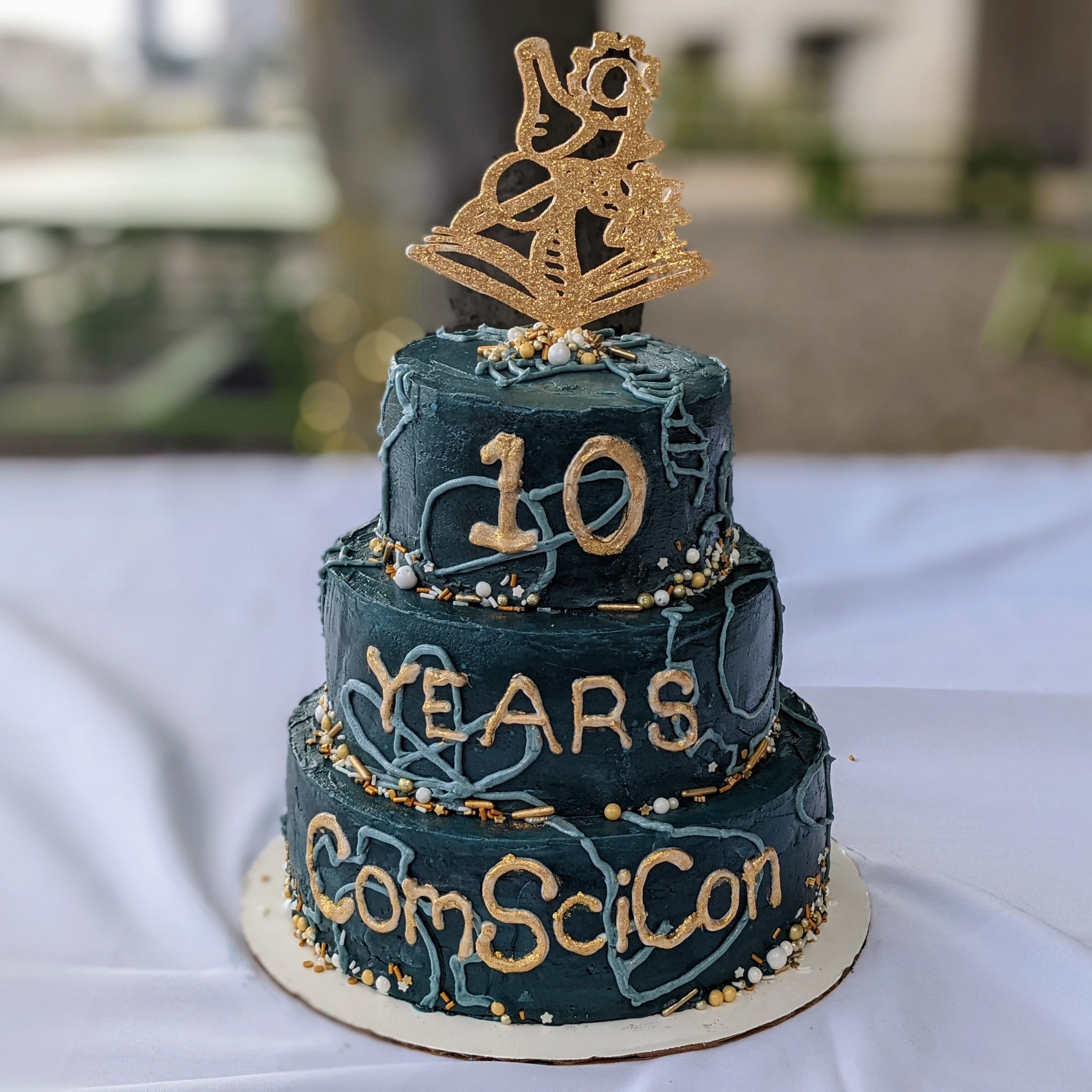 blue 3-layered cake with gold letter writing: 10 years ComSciCon
